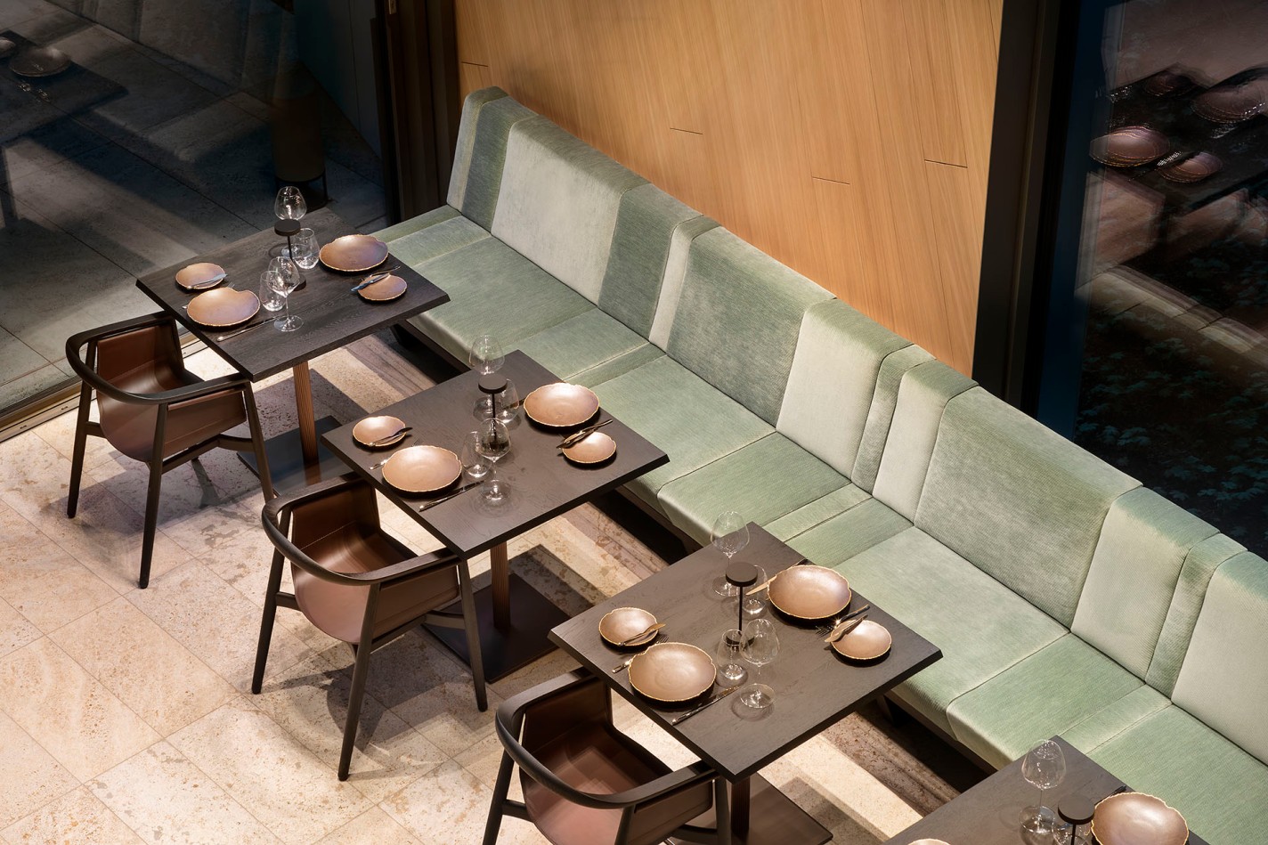 Draufsicht auf ein modernes Restaurant mit grünen Stoffsitzbänken, schwarzen Elementen in einem Raum mit Loft-Charakter