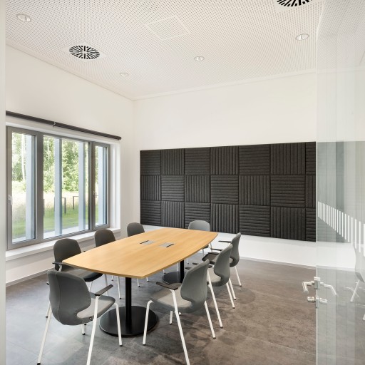 Konferenzraum mir hellem Holztisch, großer Fensterfront und anthrazitgrauen Akkustikpanelen an der Wand