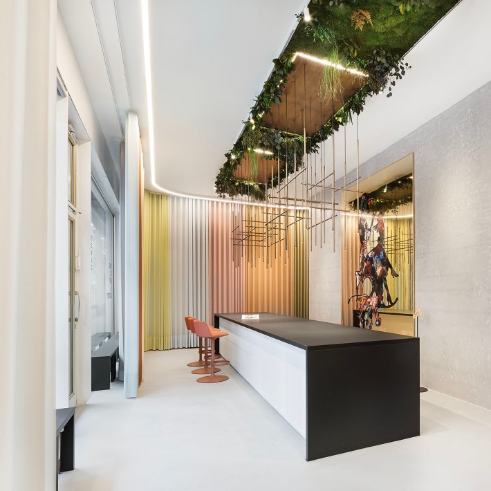 Modernes Büro mit weißen Möbeln, einer weißen Wendeltreppe und Pflanzen, die von der Decke hängend wachsen