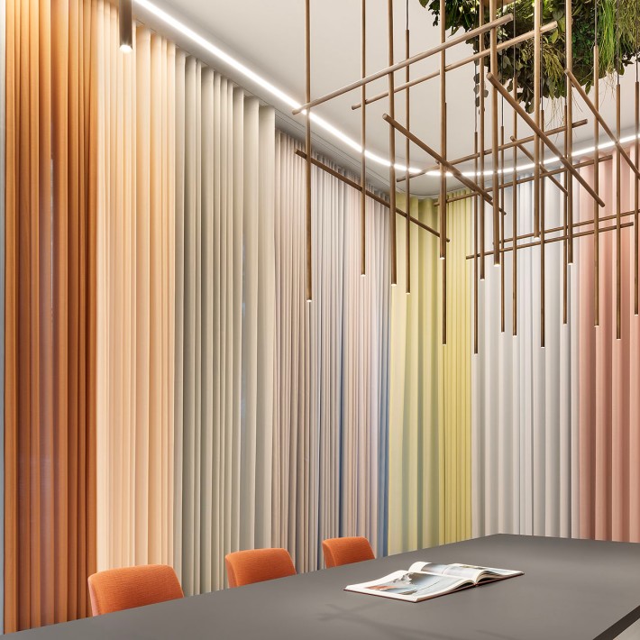 Modernes Büro mit einer kunstvollen goldenen Lampe an der Decke und Raffstores in brauen und beigefarbenen Naturtönen