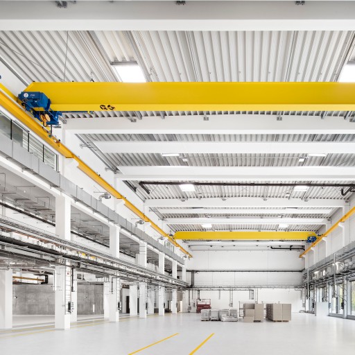 Große, weiße, leere und sehr moderne Produktionshalle mit gelben Stahlträgern und silbernen Lüftungsschächten