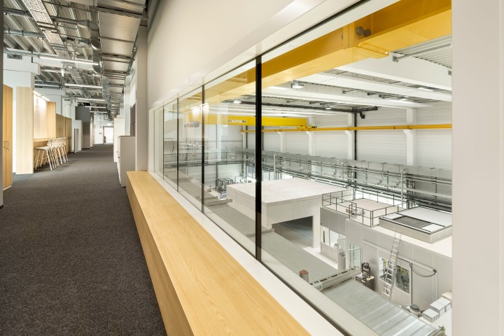 Viereckiger gläserner moderner und sehr großer Büroraum, der nach oebn offen ist und gelbe Lüftungsschächte hat