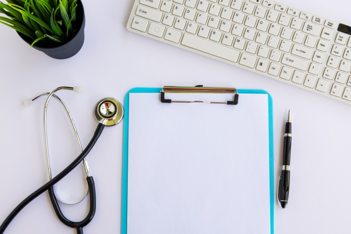 Klemmbrett, Stethoskop und Tastatur auf einem Schreibtisch 