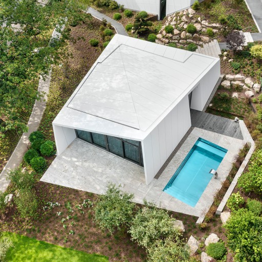 Luftaufnahme mit Blick senkrecht auf futuristische weiße Bungalow in einer mordernen Gatrneanlage mit rechteckigigem Pool