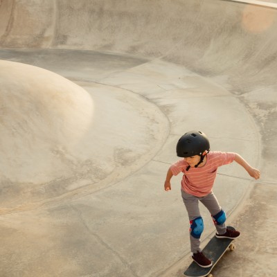 Kleiner Junge fährt in einer Halfpipe Skateboard