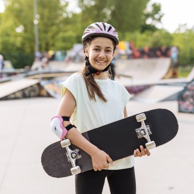 Mädchen mit einem Skatebord sieht in die Kamera