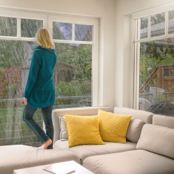 Frau im Haus am Fenster und Unwetter draußen