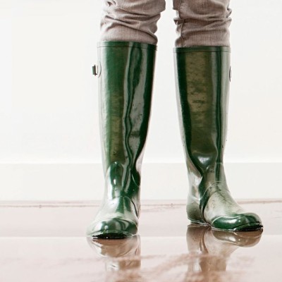 Familie sitzt vor ihrem Haus im Garten an einem Tisch, Frau lacht in die Kamera und Mann lehnt Kopf auf ihre Schulter