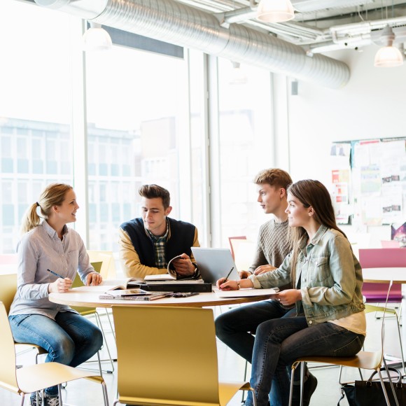 Studierende an einem runden Tisch im Austausch