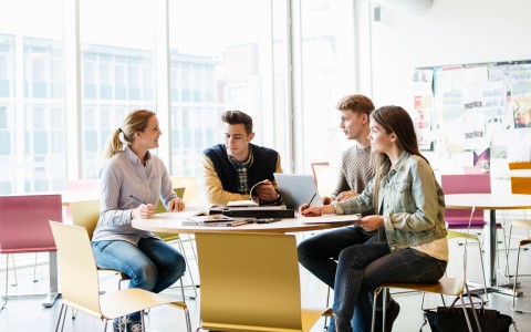 Studierende an einem runden Tisch im Austausch