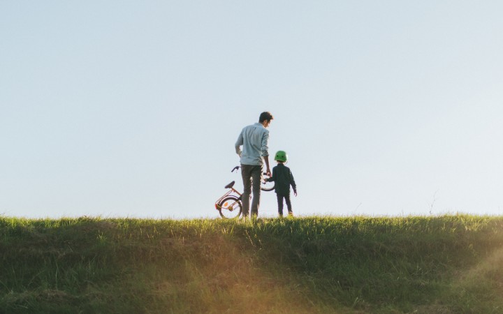 Vater und Sohn stehen mit einem Kinerfahrrad auf einem Hügel