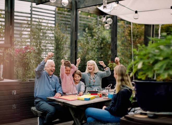 Familie am Tisch im Garten spielt ein Brettspiel