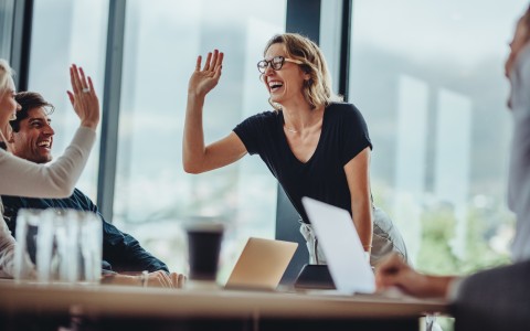 Geschäftsleute in einer Besprechung geben sich ein High Five