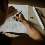 Mann am Schreibtisch zeichnet einen Grundriss