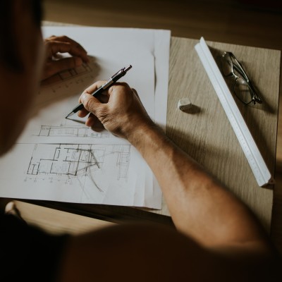 Mann am Schreibtisch zeichnet einen Grundriss