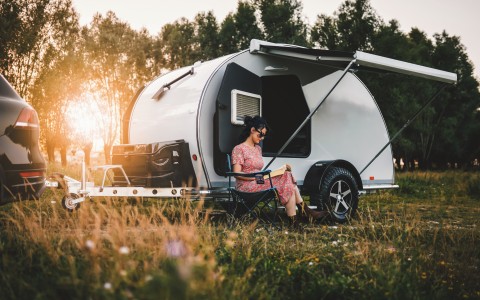 Wohnwagen mit Frau, die vor dem Wohnwagen sitzt