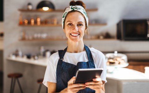 Frau mit Schürze und Tablet in der Hand 