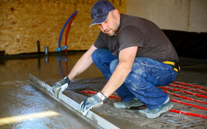 Handwerker legt Estrich auf Fußbodenheizung